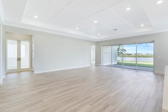 unfurnished living room featuring a tray ceiling, coffered ceiling, and light wood-type flooring