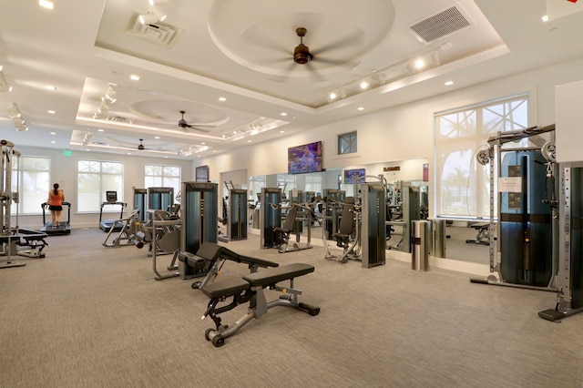 workout area with a raised ceiling and ceiling fan