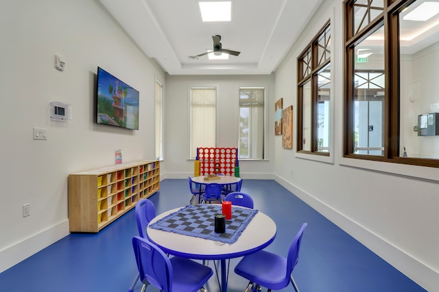 recreation room with ceiling fan and a tray ceiling