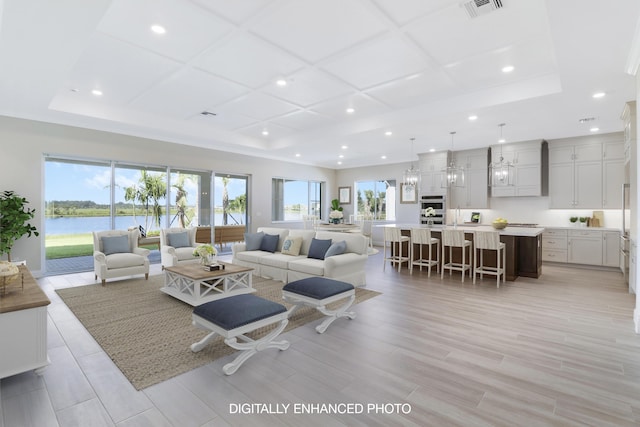 living room featuring a water view, a raised ceiling, sink, and light wood-type flooring