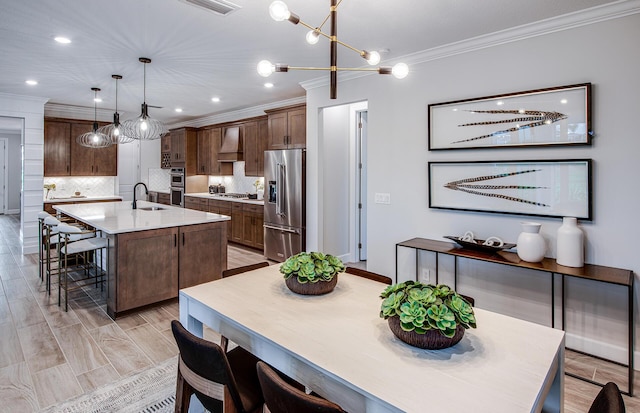 dining space featuring crown molding, sink, and light wood-type flooring