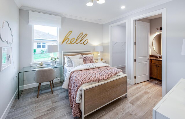 bedroom featuring multiple windows, ornamental molding, light hardwood / wood-style floors, and a tray ceiling