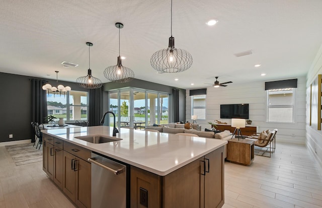 kitchen with a kitchen island with sink, sink, and hanging light fixtures