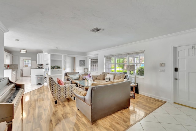 living room with crown molding, light hardwood / wood-style flooring, and washer / clothes dryer