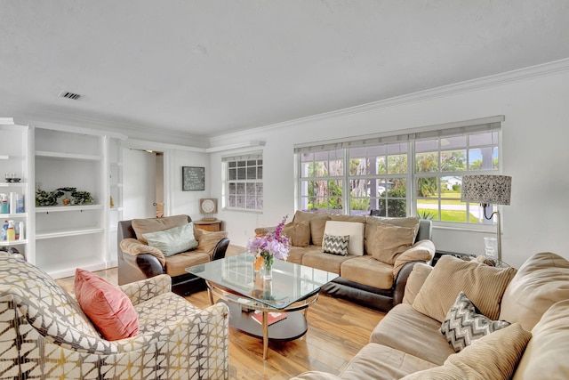 living room with ornamental molding, built in features, and light hardwood / wood-style flooring