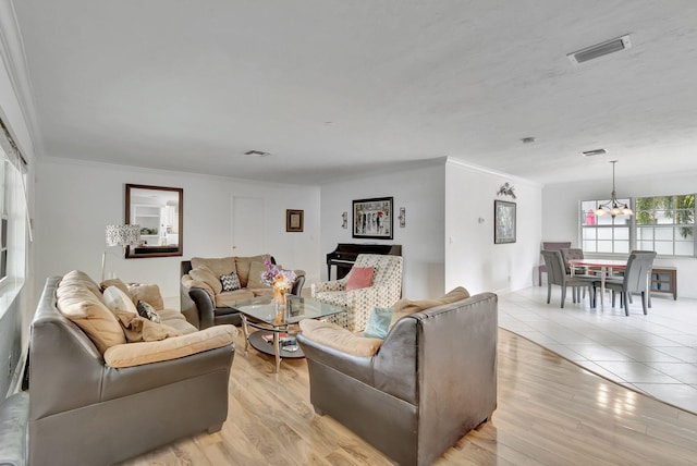 living room featuring ornamental molding, a notable chandelier, and light hardwood / wood-style floors