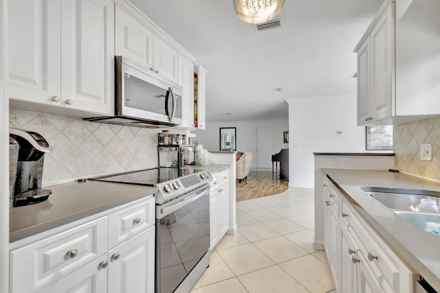 kitchen with white cabinetry, sink, decorative backsplash, appliances with stainless steel finishes, and light tile patterned flooring