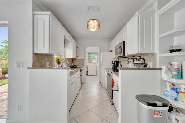 kitchen with separate washer and dryer, appliances with stainless steel finishes, white cabinetry, and backsplash