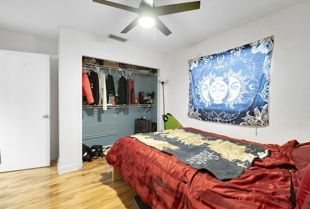 bedroom with light hardwood / wood-style flooring, ceiling fan, and a closet