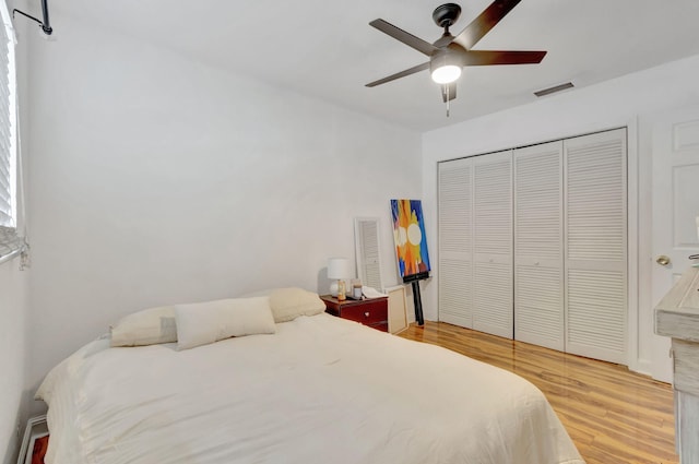 bedroom featuring light hardwood / wood-style flooring, ceiling fan, and a closet