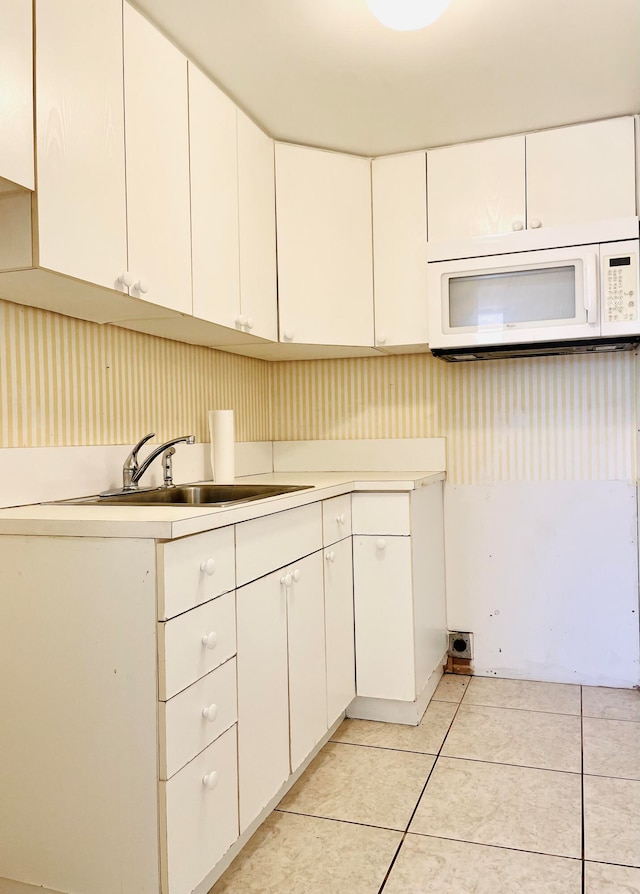 kitchen with white cabinetry, light tile patterned floors, and sink