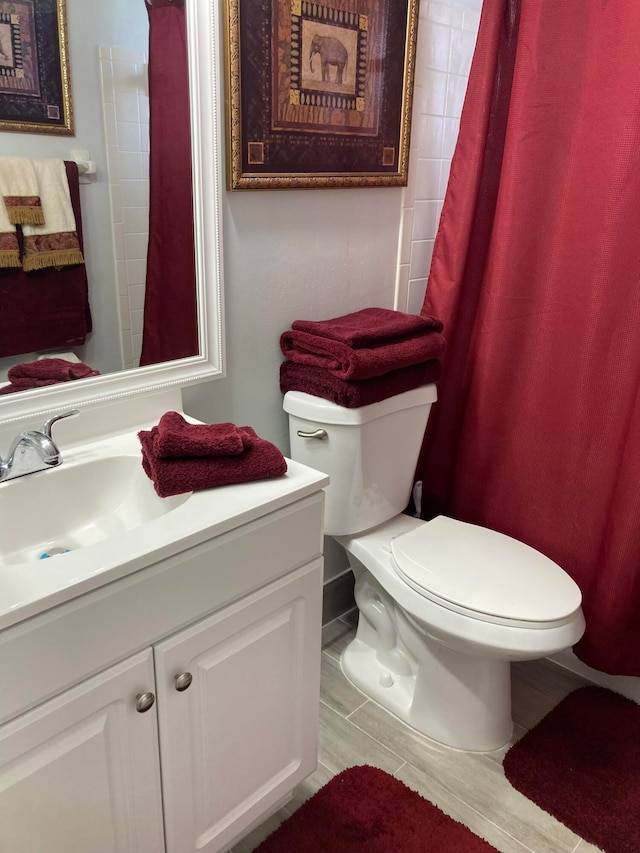 bathroom featuring toilet, vanity, and hardwood / wood-style floors