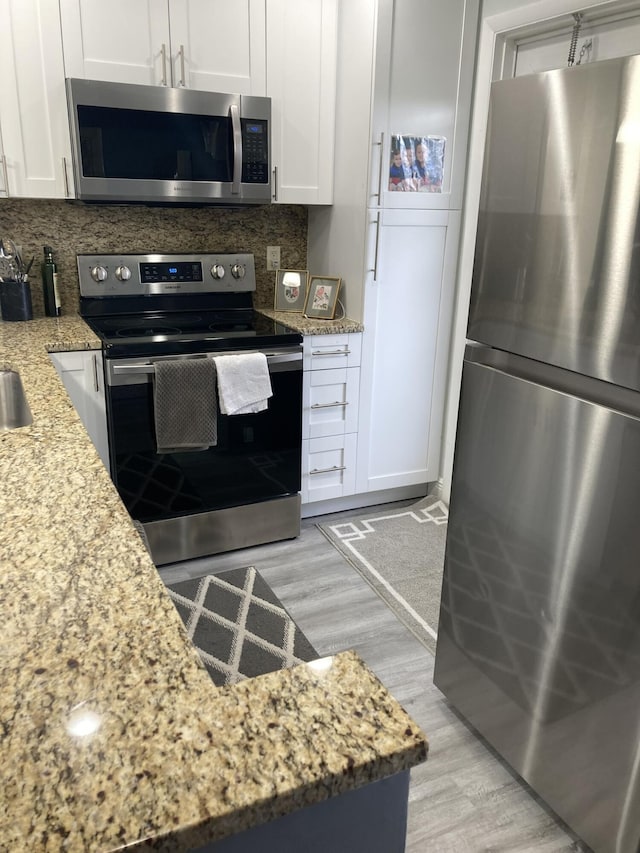 108 NE 20th Ave Unit 205, Boynton Beach, FL 33435 - kitchen featuring stainless steel appliances, light wood finished floors, decorative backsplash, and white cabinetry