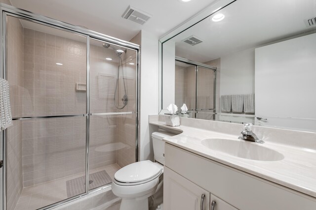 bathroom with vanity, a shower with door, and toilet