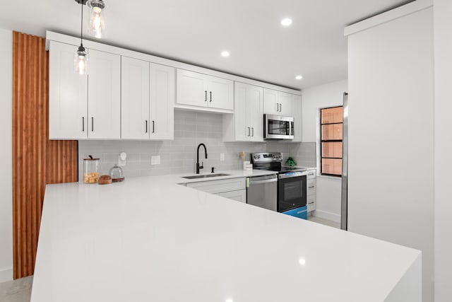 kitchen featuring white cabinetry, backsplash, stainless steel appliances, decorative light fixtures, and sink