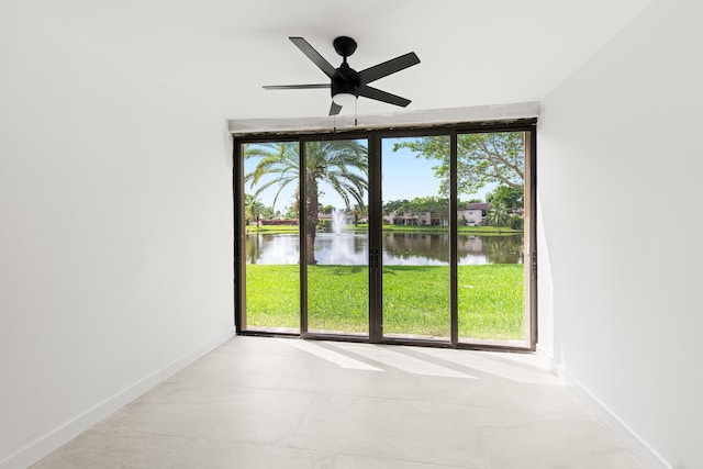 empty room with baseboards, a water view, and ceiling fan