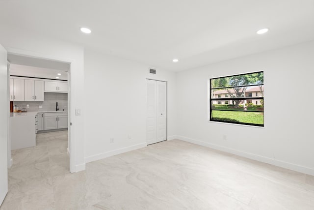 empty room featuring recessed lighting, visible vents, baseboards, and a sink