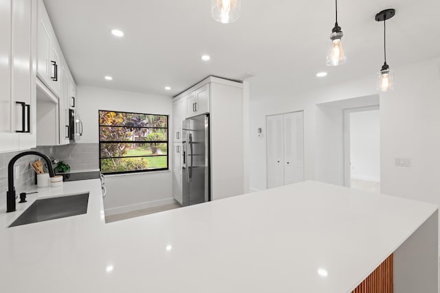 kitchen featuring white cabinets, hanging light fixtures, stainless steel appliances, sink, and kitchen peninsula