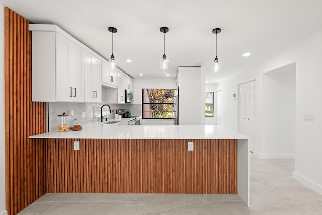 kitchen with decorative backsplash, a peninsula, light countertops, and a sink