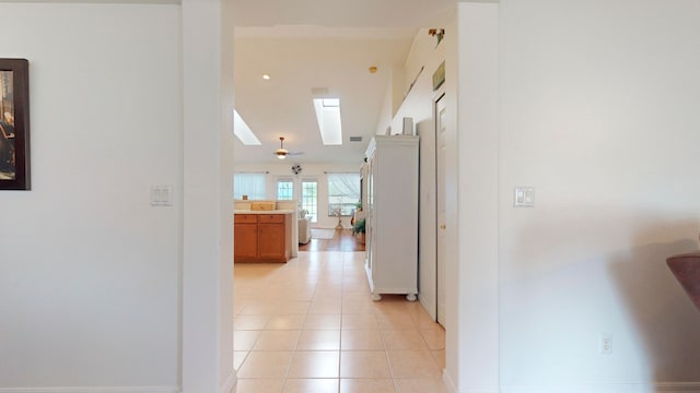 hallway featuring a skylight and light tile patterned flooring