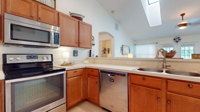 kitchen featuring light tile patterned flooring, sink, appliances with stainless steel finishes, and lofted ceiling with skylight