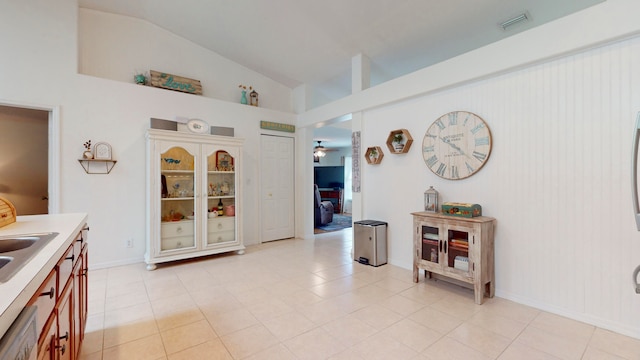 kitchen featuring dishwasher, vaulted ceiling, sink, light tile patterned flooring, and ceiling fan