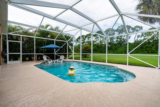 view of pool with glass enclosure, a patio area, and a yard