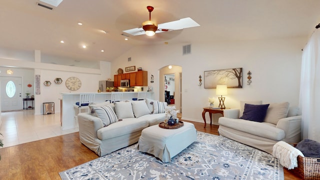 living room with light wood-type flooring, vaulted ceiling, and ceiling fan