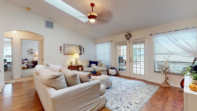 living room with lofted ceiling, plenty of natural light, wood-type flooring, and ceiling fan