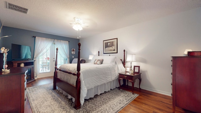 bedroom with dark wood-type flooring, ceiling fan, access to exterior, and a textured ceiling