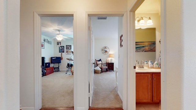 corridor with sink and light colored carpet