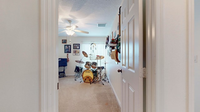 hallway featuring a textured ceiling and light colored carpet