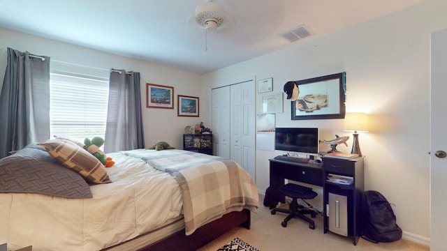 bedroom featuring light colored carpet, ceiling fan, and a closet