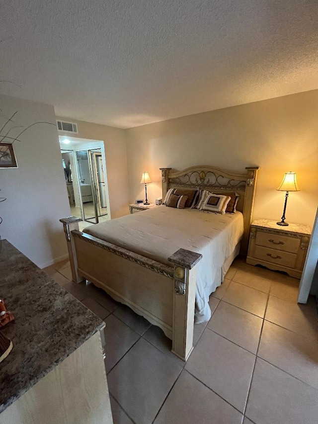 bedroom with light tile patterned floors, visible vents, and a textured ceiling