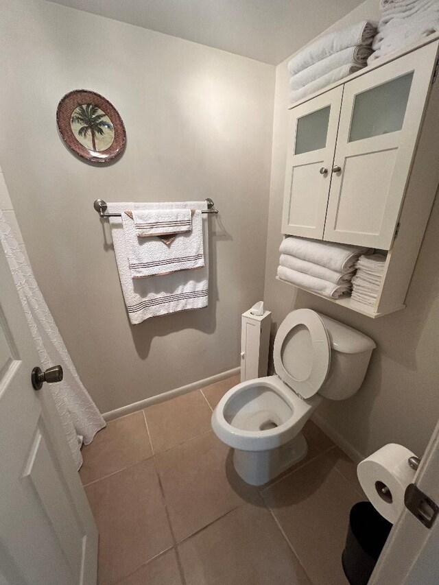 bathroom featuring toilet, tile patterned floors, and baseboards