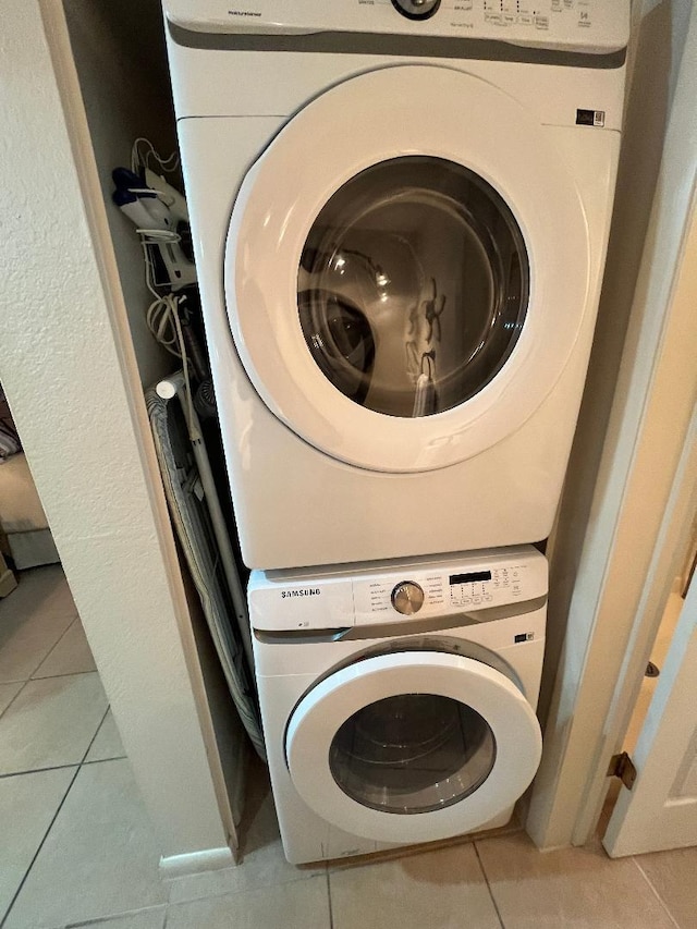 clothes washing area with light tile patterned floors and stacked washer and dryer