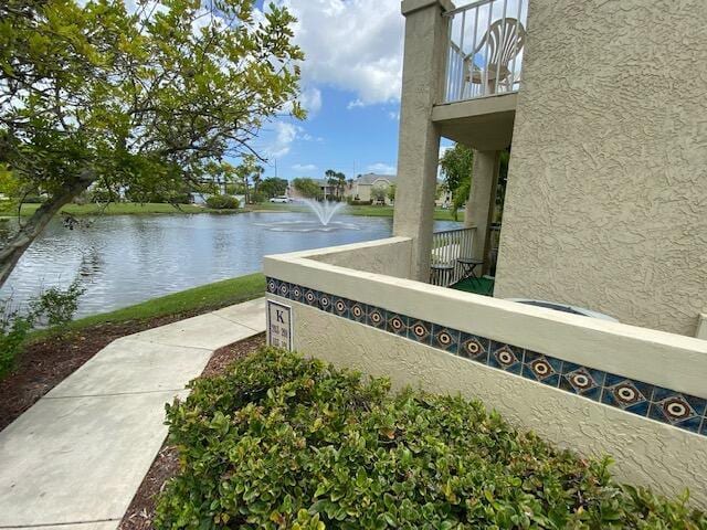 view of side of property with a balcony, stucco siding, and a water view