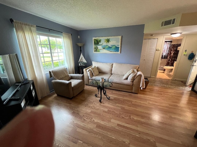 living area with visible vents, wood finished floors, and a textured ceiling