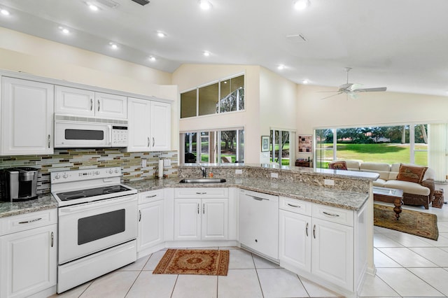 kitchen featuring light stone countertops, white appliances, kitchen peninsula, sink, and ceiling fan