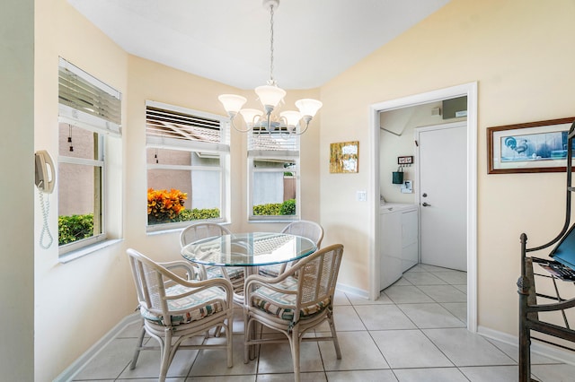 tiled dining room with lofted ceiling, an inviting chandelier, and washer and clothes dryer