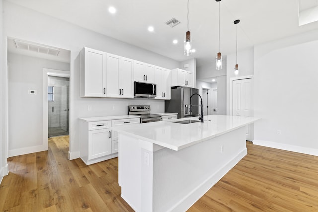 kitchen featuring stainless steel appliances, a sink, light countertops, an island with sink, and decorative light fixtures