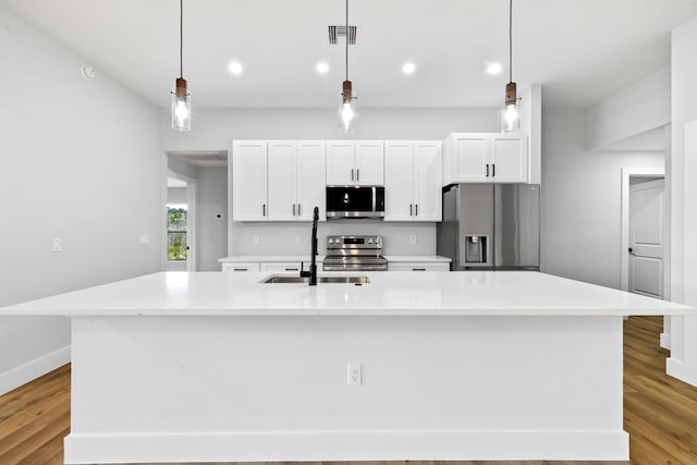 kitchen with stainless steel appliances, an island with sink, and light countertops