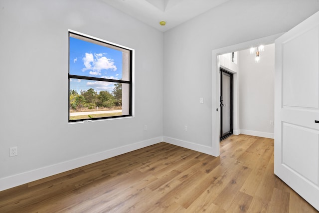 empty room featuring light wood-style flooring, baseboards, and a chandelier