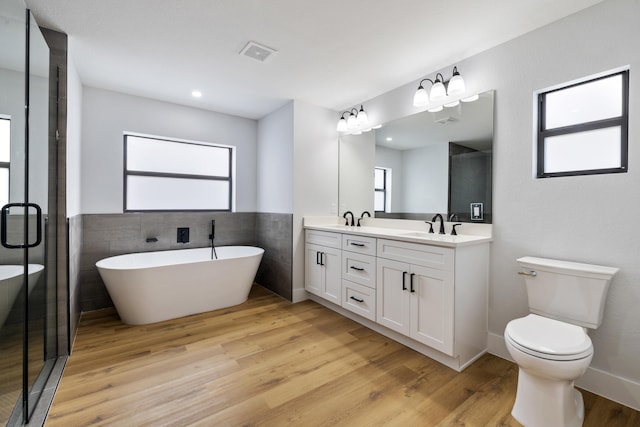 full bath featuring a freestanding tub, a sink, wood finished floors, visible vents, and double vanity