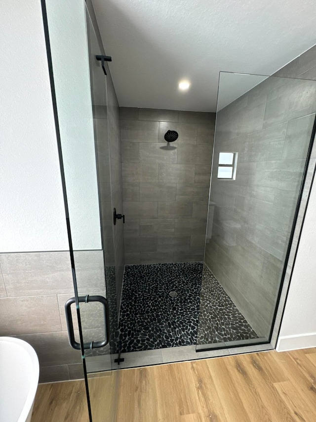 bathroom with hardwood / wood-style flooring and independent shower and bath