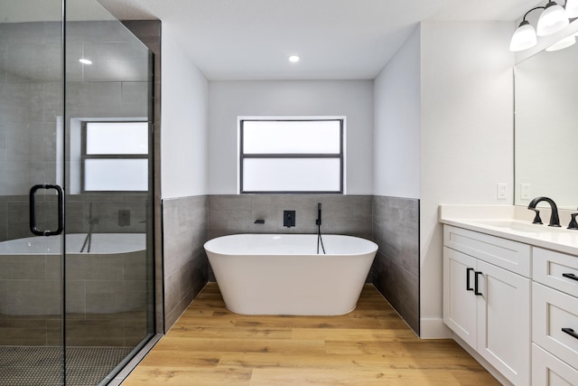 bathroom featuring a freestanding tub, vanity, a shower stall, and wood finished floors