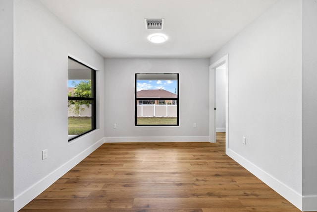 spare room featuring baseboards, visible vents, and wood finished floors