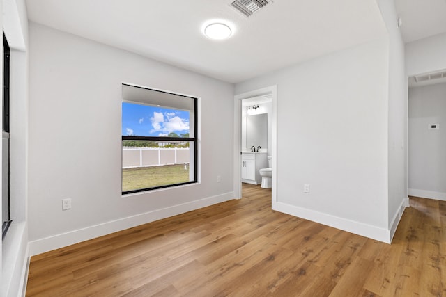 empty room featuring light wood-style flooring, visible vents, and baseboards