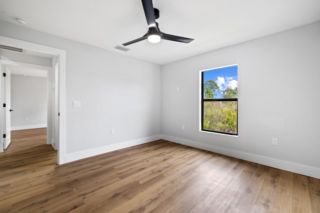 unfurnished room featuring baseboards, visible vents, ceiling fan, and wood finished floors