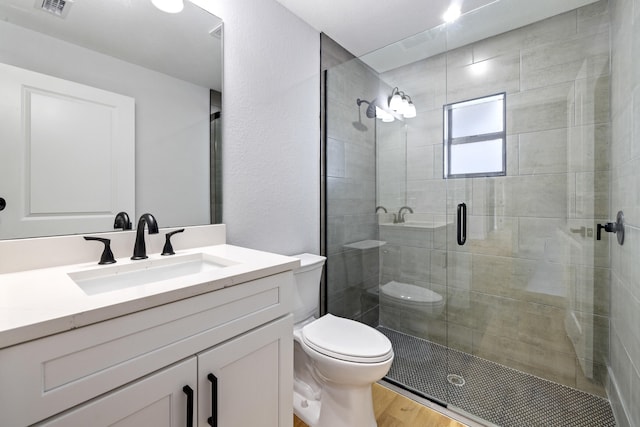 bathroom with a stall shower, visible vents, toilet, wood finished floors, and vanity